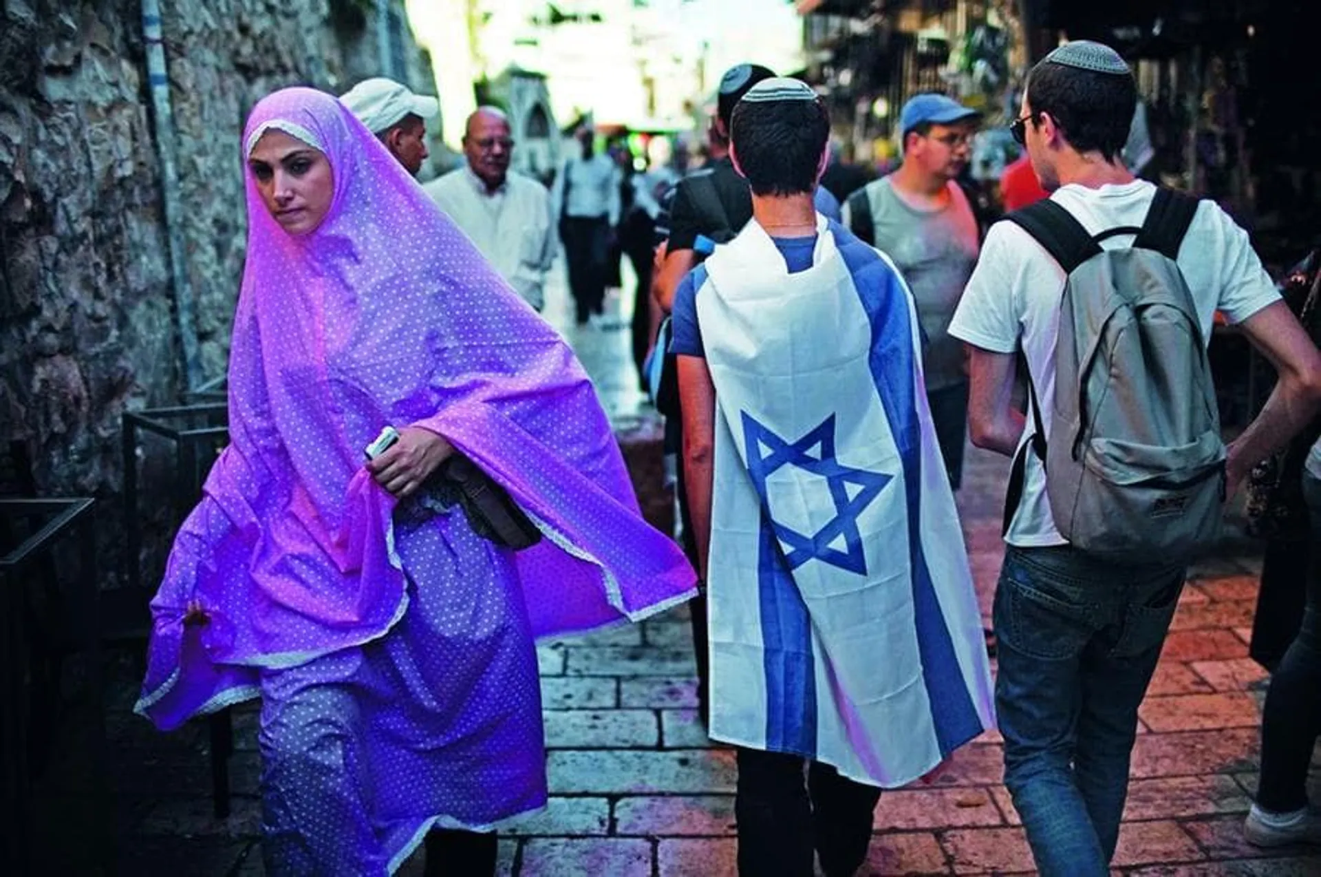 A Palestinian woman walks past Israelis marching in the old city of Jerusalem on June 1, 2011 during the Jerusalem Day parade in the city's mainly Arab eastern sector to celebrate its capture 44 years ago, during the Six Day War. AFP PHOTO /MENAHEM KAHANA (Photo credit should read MENAHEM KAHANA/AFP/Getty Images)