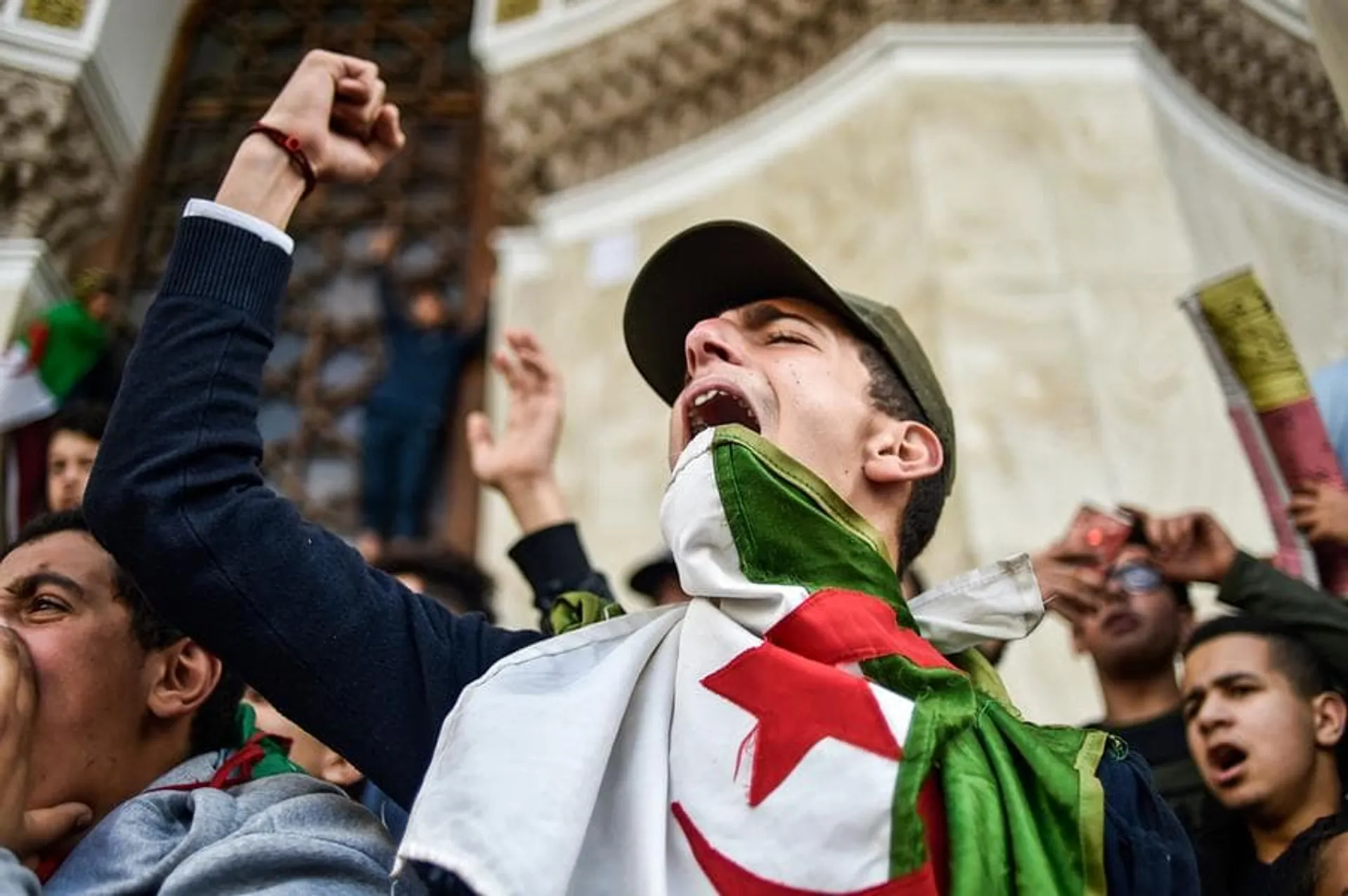 TOPSHOT - Algerian students shout slogans as they demonstrate with national flags outside La Grande Poste (main post office) in the centre of the capital Algiers on March 10, 2019 against ailing Algerian President Abdelaziz Bouteflika's bid for a fifth term. (Photo by RYAD KRAMDI / AFP)        (Photo credit should read RYAD KRAMDI/AFP/Getty Images)