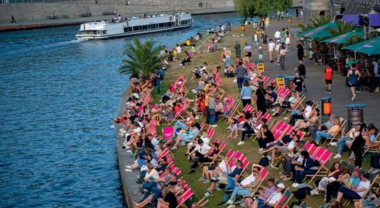 <p>Battello sul fiume Sprea e turisti al sole lungo le sue rive, a Berlino</p>
